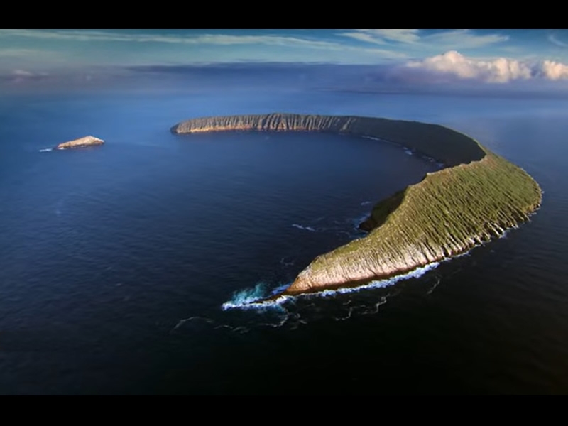 Aerial view of one of the Galapagos Islands, shaped like a crescent or the high side of part of a volcanic crater..