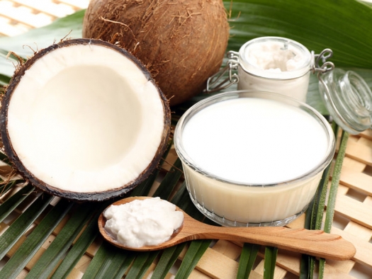 Coconut and coconut oil in jar on leaves and wooden lattice background