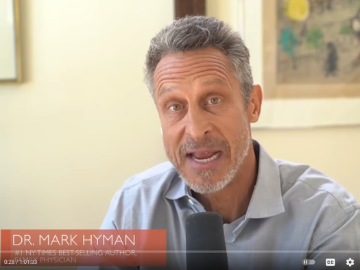 Mark Hyman seated at a table and microphone