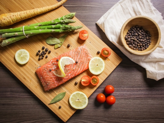 cutting board with parsnip, asparagus, salmon, lemon slices, and cherry tomatos