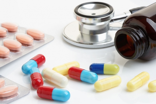 Close up of statin and beta-blocker pills and capsules with bottle and stethoscope