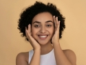 Woman in white tank top smiling.